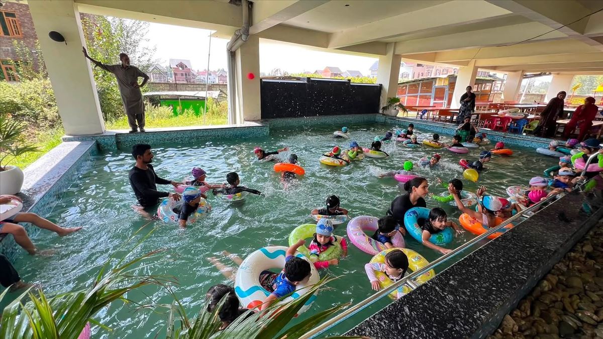 Children learning to swim with instructors in the school swimming pool at Birla Open Minds International School, HMT Srinagar